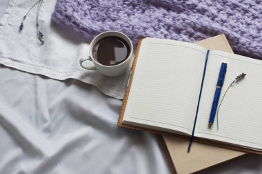 Not defteri bir fincan kahve ve bej tonlama ile bir kitap var. Günlük yaşam tarzı şal eşarp lavanta tonlama rahat arka plan