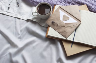 Not defteri bir fincan kahve ve bej tonlama ile bir kitap var. Günlük yaşam tarzı şal eşarp lavanta tonlama rahat arka plan