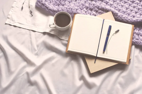 Not defteri bir fincan kahve ve bej tonlama ile bir kitap var. Günlük yaşam tarzı şal eşarp lavanta tonlama rahat arka plan