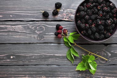 Kopya alanı karanlık bir rustik ahşap zemin üzerine bir kase taze böğürtlen. Berry, vitaminler, gıda arka plan