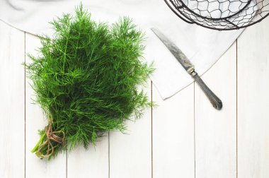 Taze dereotu bir kesim üzerinde bir bıçak ile Yönetim Kurulu ve dereotu bir ahşap masa üstü beyaz görünümde demet. Taze yeşillik, baharat, yemekler, sağlıklı bir yaşam tarzı pişirme süreci. Gıda arka plan