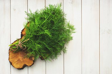 Taze dereotu bir kesim üzerinde bir bıçak ile Yönetim Kurulu ve dereotu bir ahşap masa üstü beyaz görünümde demet. Taze yeşillik, baharat, yemekler, sağlıklı bir yaşam tarzı pişirme süreci. Gıda arka plan