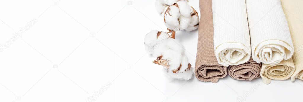 Multicolored clean towels with a branch of cotton on a white background top view with copy space. Texture of cotton, waffle towel, textiles. Towels for kitchen or Spa concept. Isolated object