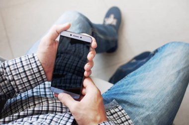 Üstten görünüm el kareli gömlekli bir smartphone kullanarak genç bir adam. Dokunmatik ekran telefon iş. Modern teknolojiler, smartphone, iş kavramı