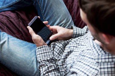 Üstten görünüm el kareli gömlekli bir smartphone kullanarak genç bir adam. Dokunmatik ekran telefon iş. Modern teknolojiler, smartphone, iş kavramı