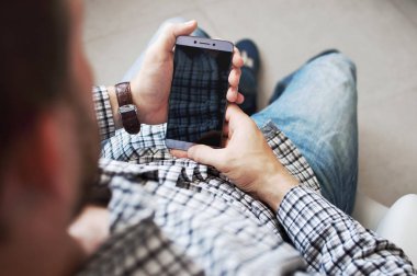 Üstten görünüm el kareli gömlekli bir smartphone kullanarak genç bir adam. Dokunmatik ekran telefon iş. Modern teknolojiler, smartphone, iş kavramı