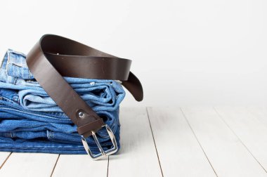 Kot pantolon ve hafif bir arka plan üzerinde bir deri kemer. Güzel kıyafetleri ve aksesuarları ayrıntılarını. Kot doku veya kot arka plan. Giyim, moda