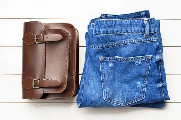 Bovenaanzicht Jeans Een Bruinleren Tas Een Lichte Houten Achtergrond Details — Stockfoto