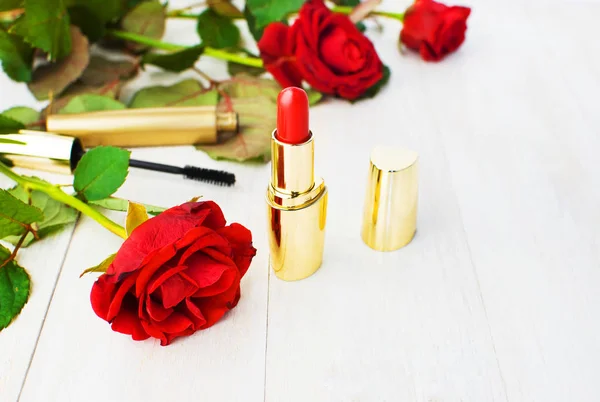 Various cosmetic products for make-up with red roses on a white wooden background with copy space. Makeup Accessories Red lipstick Black mascara Selective focus. Women's things