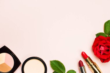 Çeşitli makyaj ürünleri kopya alanı top ile pembe bir arka plan üzerinde kırmızı gül ile düz yatıyordu görüntüleyin. Kadınsal