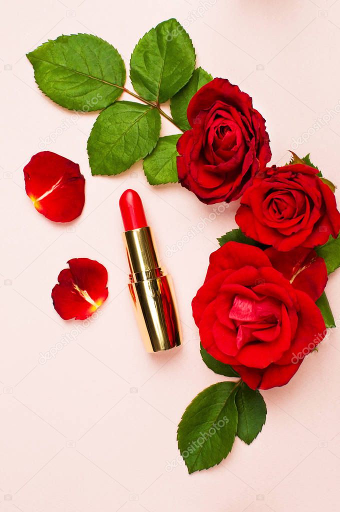 Red lipstick with red roses on pink background with copy space. Makeup Accessories Top view Flat Lay. Various cosmetic products for make-up. Women's things