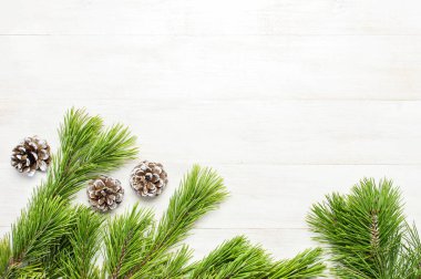 Noel arka plan, yeşil Çamın dalları, kar beyaz ahşap masa üzerinde süslenmiş koniler. Kenarlık ve kopya alanı tasarım en iyi görünümü ile yaratıcı kompozisyon. Yeni yıl, tatil, dekorasyon