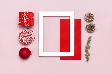 Noel kompozisyon. Beyaz fotoğraf çerçevesi, kırmızı zarf, çam dalları, koniler, top, sicim, Hediyelik, pembe bir arka plan düz Ahşap oyuncaklar üstten görünüm yatıyordu. Noel Kış dekorasyonu yeni yıl, tatil nesneleri