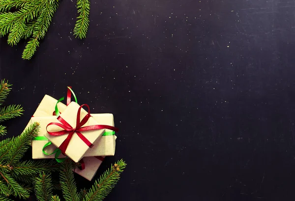 Традиційний різдвяний темний фон вид зверху. Новорічні подарунки з червоно-зеленою стрічкою Гілка ялини — стокове фото