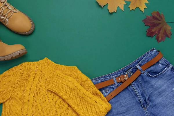 女性橙色针织毛衣 蓝色牛仔裤 靴子和秋叶绿色背景背景景观平躺式时尚女士服装集时尚舒适针织秋季配件女性时尚造型 — 图库照片