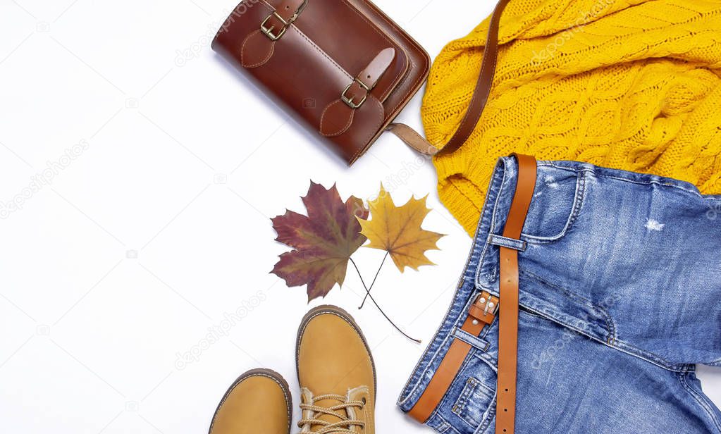 Female orange knitted sweater, blue jeans, leather bag, boots and autumn leaves on white background top view flat lay Fashion Lady Clothes Set Trendy Cozy Knit Jumper Autumn accessories Female fashion look