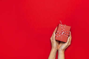 Hediye kutusu ile dekoratif dantel eller kırmızı arka plan en iyi görünüm düz içinde yatıyordu. Tatil kavramı yeni yıl veya Noel hediye kutusu Xmas tatil tebrikler arka plan metin için yer sunar