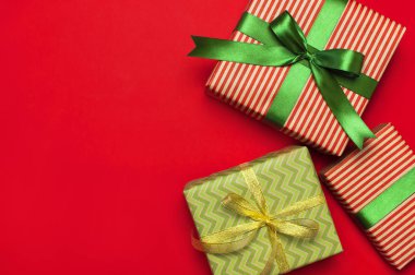 Hediye kutuları kırmızı arka plan en iyi görünüm düz yeşil şerit ile yatıyordu. Tatil kavramı, yeni yıl veya Noel hediye kutusu, Xmas tatil sunar. Tebrikler arka plan metin için yer ile.