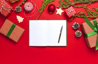 Açık defter ile boş sayfalar, hediye kutuları, köknar kırmızı bir arka plan düz dallarda üstten görünüm yatıyordu. Noel planlama kavramı tatil dekorasyon 2019 gol. Yeni yıl Noel, kış dekorasyonu