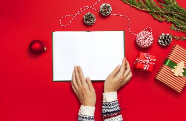 Noel süslemeleri 2019 gol kış tatil kavramı planlama çam dalları üzerinde kırmızı bir arka plan düz örme kazak tutar açık temiz defter, hediye kutuları, kadın el koyma