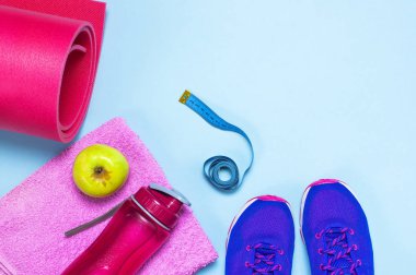 Fitness kavramı ile Ultra mor pembe kadın spor ayakkabı, su şişesi, havlu üstten görünüm elma pastel mavi arka plan düz üzerinde yatıyordu. Spor ayakkabı, sağlıklı erkek fitness kavramı.