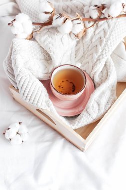 Pamuk ahşap tepsi dalı sıcak çay fincan beyaz keten ile yatakta kareli kazak ördü. Rahat sabah kahvaltı evde yaşam tarzı nazik kadın arka plan kopya alanı sonbahar kış kavramı
