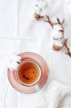 Bir fincan sıcak çay, hassas pamuk ve beyaz keten ile yatakta ekose kazak örme dalı. Rahat sabah kahvaltı evde yaşam tarzı nazik kadın arka plan kopya alanı sonbahar kış kavramı