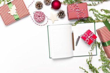 Açık defter ile boş sayfalar, hediye kutuları, beyaz arka plan düz dallarda köknar üstten görünüm yatıyordu. Noel planlama kavramı tatil dekorasyon 2019 gol. Yeni yıl, Noel Kış dekorasyonu