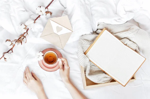 Hassas pamuk çiçek açık defter aşk mektubu tepsi beyaz örgü kazak yatakta sıcak çay Kadınlar Elele tutuşun. Sabah kahvaltı evde rahat yaşam tarzı kopya alanı sonbahar kış konsepti