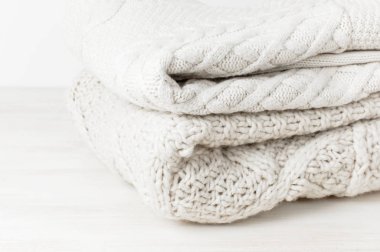 Açık renkli ahşap tablo üzerinde bir yığın halinde iki beyaz örgü yün kazak kazak. Moda giyim moda rahat Jumper. Sonbahar ve kış giysileri için metin alanı