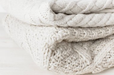 Açık renkli ahşap tablo üzerinde bir yığın halinde iki beyaz örgü yün kazak kazak. Moda giyim moda rahat Jumper. Sonbahar ve kış giysileri için metin alanı