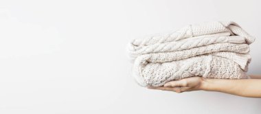 İki beyaz ışık arka plan üzerinde eller yığınında yün kazak kazak ördü. Moda giyim moda rahat Jumper. Sonbahar ve kış giysileri için metin alanı