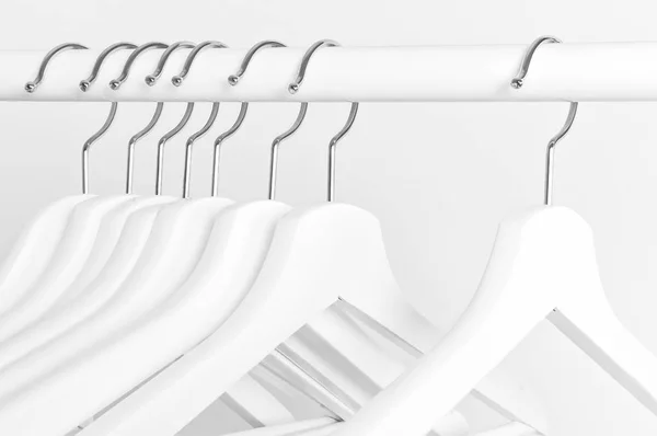 Veel Houten Witte Hangers Een Stang Geïsoleerd Een Witte Muur — Stockfoto