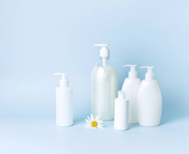 Kozmetik şişe kapları mavi minimalist arka plan düz üzerinde papatya çiçeği ile yatıyordu. Mock-up marka için boş etiket. Doğal güzellik ürün kavramı