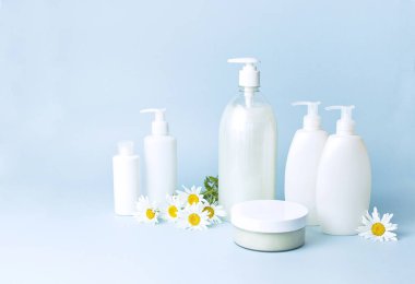 Kozmetik şişe kapları mavi minimalist arka plan düz üzerinde papatya çiçeği ile yatıyordu. Mock-up marka için boş etiket. Doğal güzellik ürün kavramı