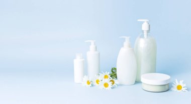 Kozmetik şişe kapları mavi minimalist arka plan düz üzerinde papatya çiçeği ile yatıyordu. Mock-up marka için boş etiket. Doğal güzellik ürün kavramı