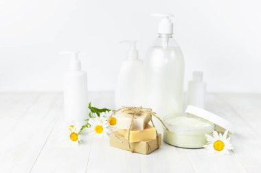 Plastik Konteyner krem, el yapımı sabunlar, beyaz Kozmetik şişe kapsayıcılar ve beyaz bir arka plan üzerinde papatya çiçek açtı. Bitkisel Dermatoloji kozmetik Spa konsept organik kozmetik doğal