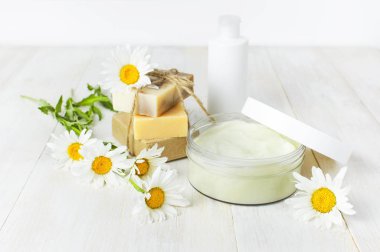 Plastik Konteyner krem, el yapımı sabunlar, beyaz Kozmetik şişe kapsayıcılar ve beyaz bir arka plan üzerinde papatya çiçek açtı. Bitkisel Dermatoloji kozmetik Spa konsept organik kozmetik doğal