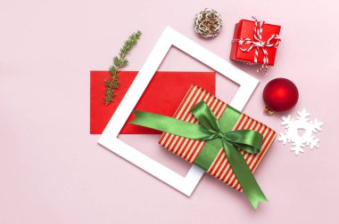 Noel kompozisyon. Beyaz fotoğraf çerçevesi, kırmızı zarf, çam dalları, koniler, top, sicim, Hediyelik, pembe bir arka plan düz Ahşap oyuncaklar üstten görünüm yatıyordu. Noel Kış dekorasyonu yeni yıl, tatil nesneleri