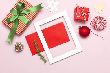 Noel kompozisyon. Beyaz fotoğraf çerçevesi, kırmızı zarf, çam dalları, koniler, top, sicim, Hediyelik, pembe bir arka plan düz Ahşap oyuncaklar üstten görünüm yatıyordu. Noel Kış dekorasyonu yeni yıl, tatil nesneleri