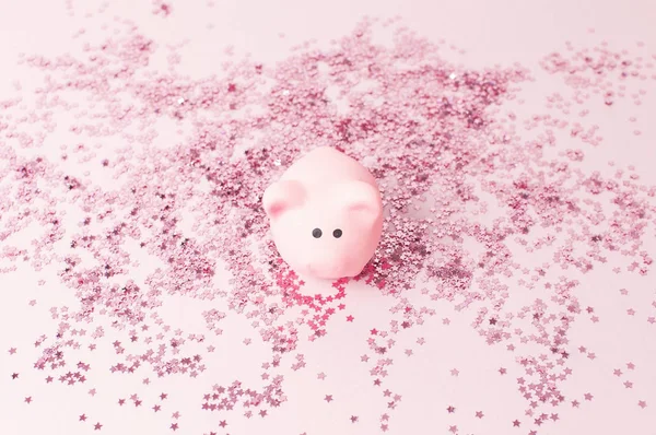 Ceramic toy pink pig symbol of the new year and holographic glitter confetti form of stars on pink background Flat Lay copy space. Decoration Festive decor celebration Xmas holiday