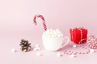 Marshmallow Candy Cane, kırmızı hediye kutusu, çam kozalağı, pembe bir arka plan düz yatıyordu kış geleneksel içecek yiyecek şenlikli dekor yılbaşı yeni yıl üzerinde dekoratif dantel ile beyaz kupa Xmas tatil sunar
