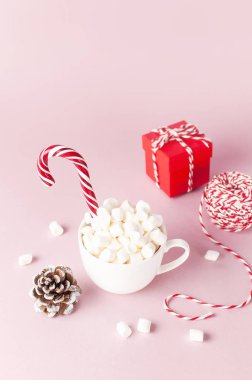 Marshmallow Candy Cane, kırmızı hediye kutusu, çam kozalağı, pembe bir arka plan düz yatıyordu kış geleneksel içecek yiyecek şenlikli dekor yılbaşı yeni yıl üzerinde dekoratif dantel ile beyaz kupa Xmas tatil sunar