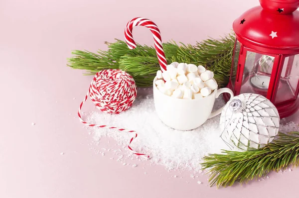White mug with marshmallows Candy Cane, gifts boxes pine branches Christmas New Year ball packaging lace flashlight in the snow on pink background Flat Lay Winter traditional drink food Festive decor