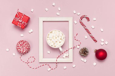 Marshmallow Candy Cane hediyeler ile beyaz kupa kırmızı top dantel fotoğraf çerçevesi pembe arka plan en iyi görünüm düz yatıyordu ambalaj kutuları. Kış geleneksel içecek yiyecek şenlikli dekor kutlama Noel yeni yıl