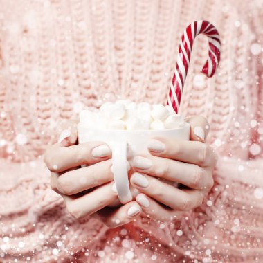 Yılbaşı yeni yıl içecek, şekerleme erkek ile beyaz kupa örme pembe kazak ve şeker kamışı eller. Kış geleneksel gıda Festival içki kutlama karlı etkisi