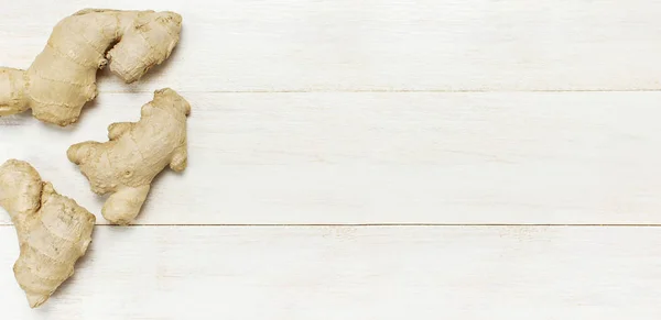 Fresh Ginger root on white wooden background top view with copy space. Minimalistic style, seasoning, spice, ingredient for tea. Concept healthy food, medicine improving immunity
