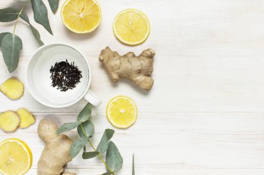 Taze zencefil kökü, fincan çay içinde bira, limon, okaliptüs ile beyaz ahşap zemin üzerine bırakır. Yat, görünümü, kopya alanı top. Minimalist tarzı, baharat, çay için baharat madde.