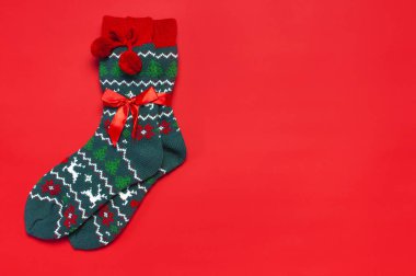Kırmızı arka plan en iyi görünüm düz lay üzerinde Noel yılbaşı süsleme ile yün çorap. Tatil kavramı, şenlikli çorap, Xmas sunar. Tebrikler arka plan metin için yer ile soğuk için elbise