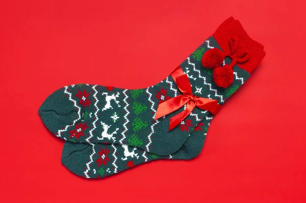 Woolen socks with a Christmas New Year ornament on red background top view flat lay. Holiday concept, Festive socks, presents Xmas. Congratulations background with space for text Clothes for the cold